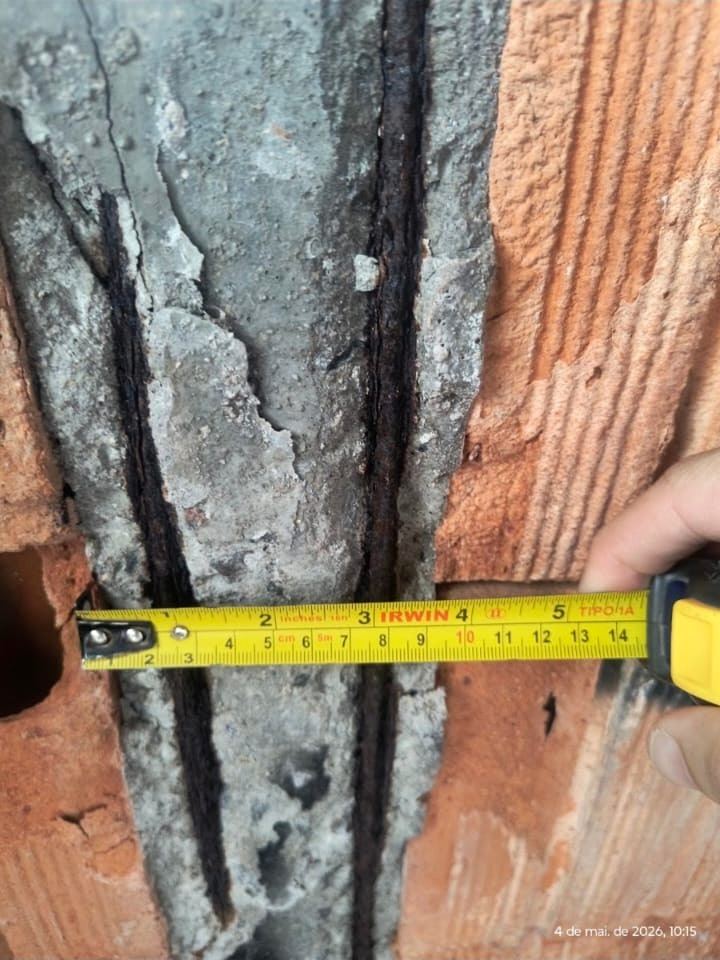 Trena posicionada sobre fissura profunda entre alvenaria cerâmica e elemento de concreto.