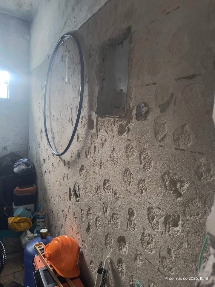 Parede com o revestimento removido em vários pontos, expondo o substrato para inspeção.